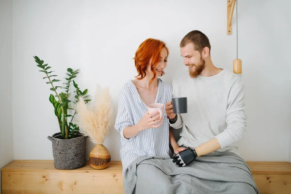 Feliz marido y mujer sentados juntos en un estante, tomando café en casa . — Foto de Stock