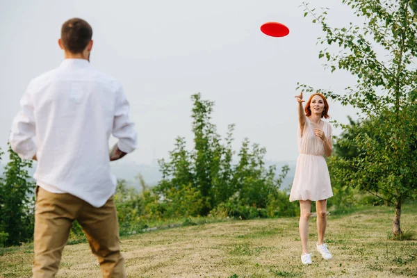 Hombre y mujer jugando frisbee en un parque al lado de un río y una cresta forestal —  Fotos de Stock