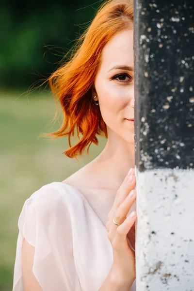 Junge Frau mit Ingwer gefärbten Haaren, die hinter einem Pfosten hervorlugt — Stockfoto