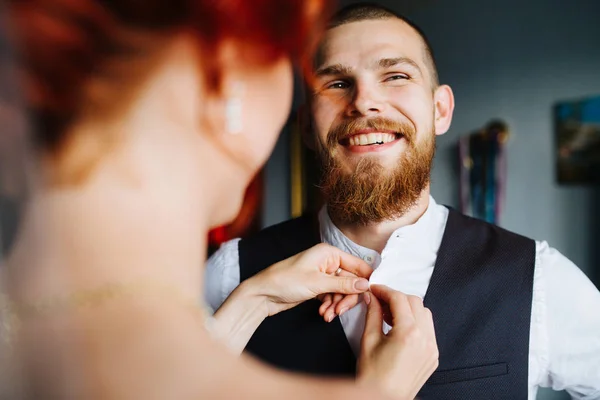 Невеста застегивает рубашку своего будущего мужа перед свадьбой — стоковое фото