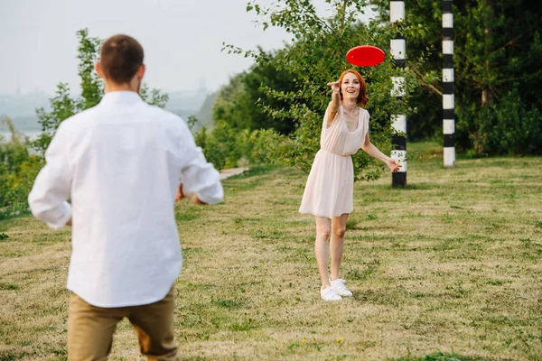 Hombre y mujer jugando frisbee en un parque al lado de un río y una cresta forestal — Foto de Stock