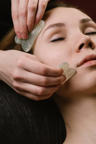 Close up de uma jovem mulher ter um gua sha rosto massagem no asiático beleza clínica . — Fotografia de Stock