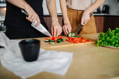 Mutfakta sebze doğrayan iki kişinin elleri.