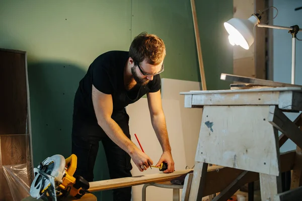 Un homme qui travaille sur la rénovation de son appartement. Mesurer la planche avec un mètre à ruban . — Photo