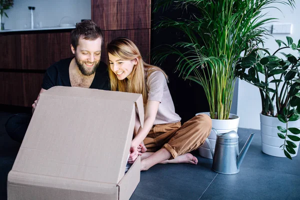 Pareja feliz mirando dentro de una caja, brillando desde dentro — Foto de Stock