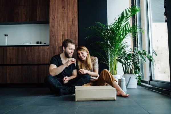 Longshot de um casal sentado em um andar com chaves para seu novo apartamento . — Fotografia de Stock