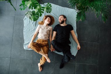 Çarşaflarla kaplı yerde yatan gülen genç bir çift. Yeni taşındılar..