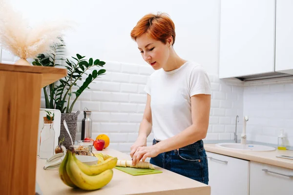 Emotionless Focused Middle Aged Woman Short Ginger Hair Slicing Banana — Stok fotoğraf