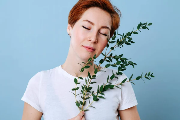 Relaxed woman with short ginger hair holding eucalyptus branch. — Stock Photo, Image