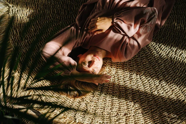 Мирная Молодая Женщина Розовом Платье Лежащая Плетеном Ковре Освещенная Солнечным — стоковое фото