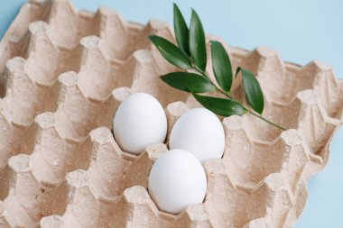 Basit Paskalya bayramı süslemeleri. Mavi arka planda çevre dostu ambalajlı güzel beyaz yumurtalar.