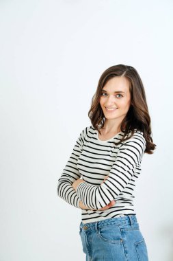 Hoş bir genç kızın portresi, beyaz bir duvarın arkasında çizgili ceket ve kot pantolon giyiyor.