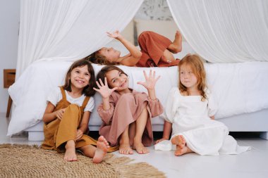 Aynı yaşlarda dört tatlı kız çift kişilik bir yatakta perdelerle takılıyorlar. Hepsi elbise giyiyor. Biri yatağa uzanıyor, üçü üzerine yaslanıyor, yerde oturuyor..