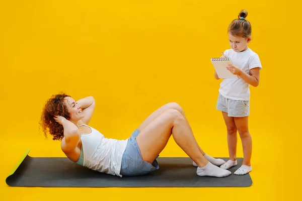 Moeder Doet Persoefeningen Dochter Schrijft Mama Trainingsresultaten Notitieblok Afbeelding Gele — Stockfoto