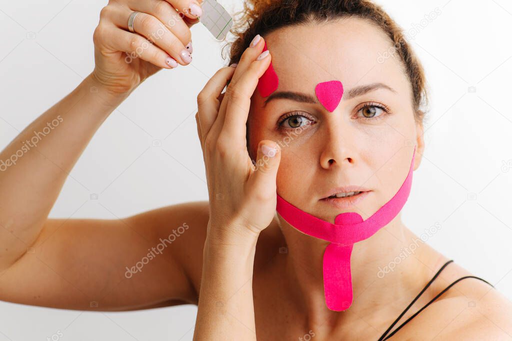 Woman, she sticks a kinesiological tape on her face