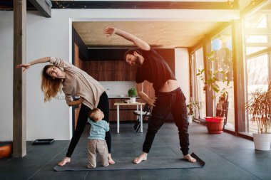 Çiftler egzersizlerinin bir parçası olarak yan yatarken, çocukları annesinin gömleğini çekiştirip ilgi ararlar. Aile karantinası, kendini izole eden aile hayatı. Pencerelerden gün batımı ışığı