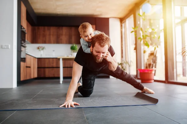 Babası spor yapıyor, boynunda bebek yavrusuyla tek kollu tahta yapıyor. Evinde kal. Aile karantinası, kendini izole eden aile hayatı. Pencerelerden gün batımı ışığı
