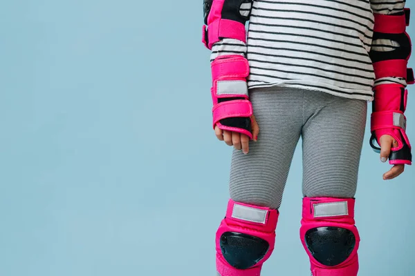 青い背景の上にローラースケートのための縞模様の服とピンクの保護具で女の子のイメージを閉じます 体の中央部だけで頭はない — ストック写真
