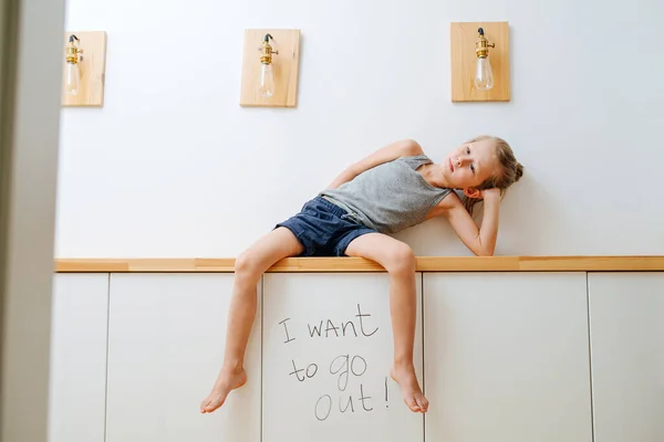 小男孩坐在走廊架子上的一块木板上 说他想出去走走 厌倦了在自我封闭的环境中坐在家里 — 图库照片