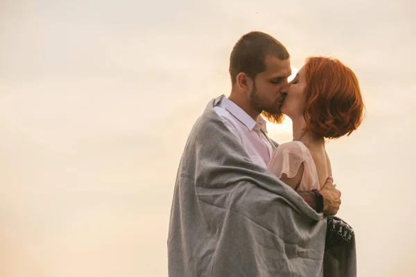 Loving Couple Kissing Enveloped Blanket Overcast Sky Orange Setting Sun — 스톡 사진