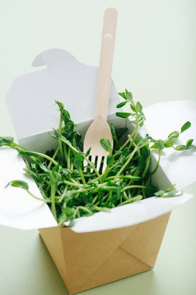 竹叉粘贴在纸盒上 满是豌豆芽 背景为绿色 可处置 可回收的无害生态产品 靠近点 — 图库照片