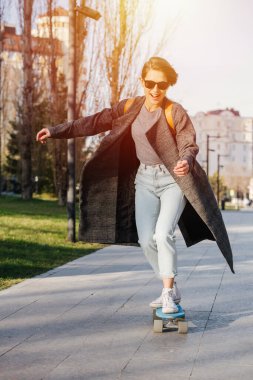 Çekici beyaz bir kadının duygusal portresi, paten kayıyor. Paltosu yelkenler gibi çırpınıyor..