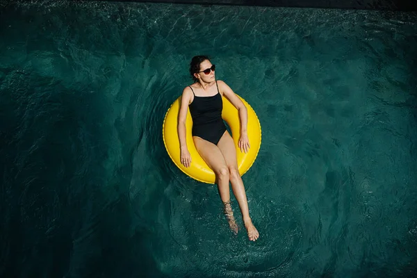 Młoda Kobieta Czarnym Stroju Kąpielowym Okularach Przeciwsłonecznych Pływająca Basenie Żółtej — Zdjęcie stockowe