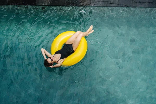 Młoda Kobieta Czarnym Stroju Kąpielowym Okularach Przeciwsłonecznych Pływająca Basenie Żółtej — Zdjęcie stockowe