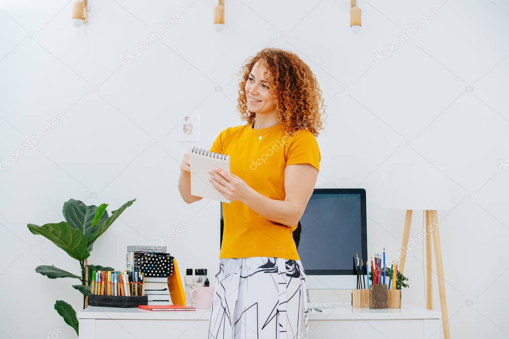 Portrait of smiling artist woman drawing in her notepad with crayon