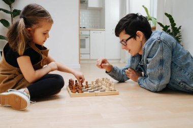 Mutlu baba ve küçük kızı evdeki mutfak zemininde satranç oynuyorlar. Yan görünüm