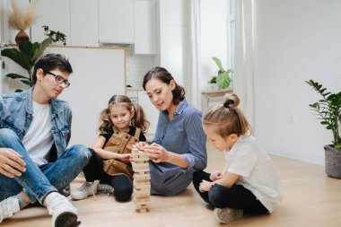 Anne, babam mutfakta çocuklarla oynuyor, ahşap bloklardan kule inşa ediyor, devrilene kadar sırayla fayanslar alıyor. Çocuklarla tecritte vakit geçirmek.