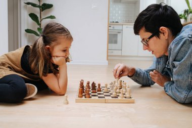 Mutlu baba ve küçük kızı evdeki mutfak zemininde satranç oynuyorlar. Yan görünüm