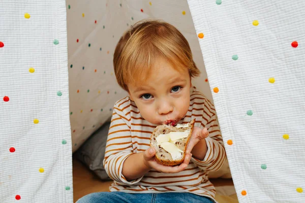 Bir Kulübede Ekmek Tereyağı Yiyen Sevimli Küçük Bir Çocuk Kameraya — Stok fotoğraf