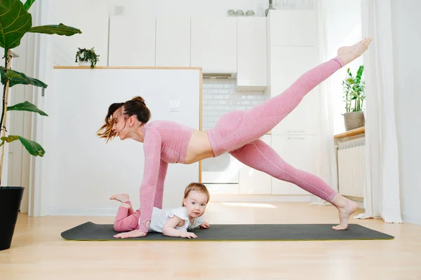 Young Mother Sportswear Practices Gymnastics Home Standing Bar Alternately Raises — Stock Photo, Image