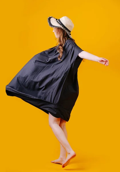 Portakal rengi arka planda kanat çırpan elbisesi olan bir kadının yan resmi. — Stok fotoğraf