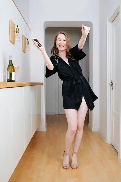 Girl partying at home alone. Shes listening music, dancing and drinking wine. — Stock Photo, Image