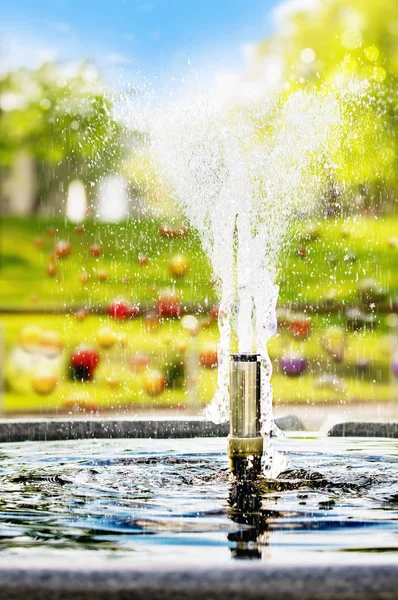 Small decorative fountain in a park in a blurry background