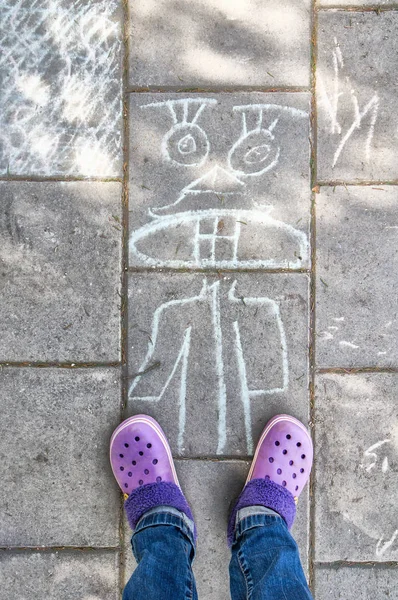Girls\' legs with  a purple shoes on the pavement with chalk draw