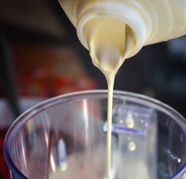 Plastik şişeden bir kasenin içine dökülür varlık krem. Yakın çekim.