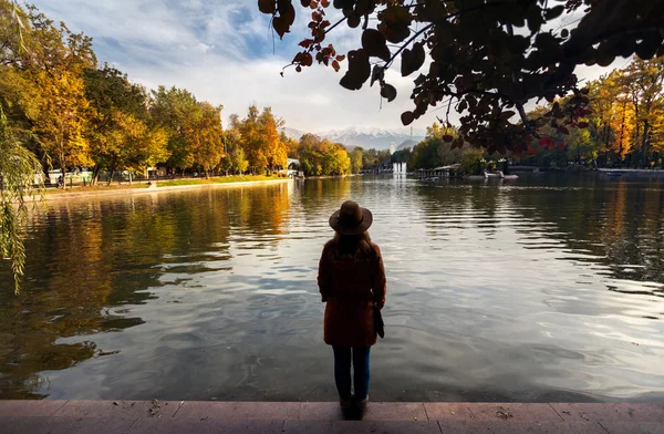 Mulher perto do lago no parque de outono — Fotografia de Stock