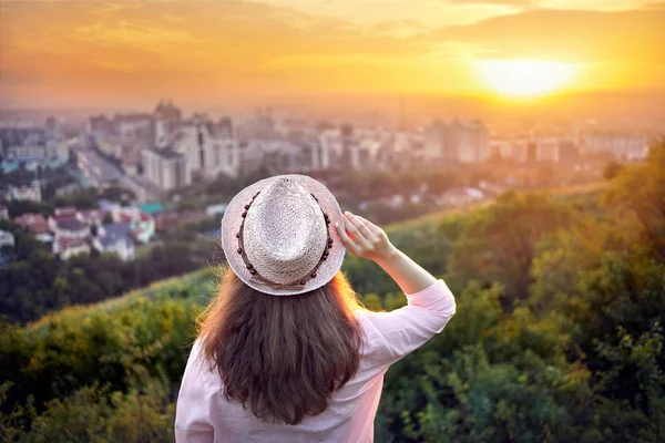 在夕阳的城市景观的帽子的女人 — 图库照片