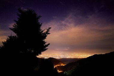 Gece şehir ve yıldızlı gökyüzünün