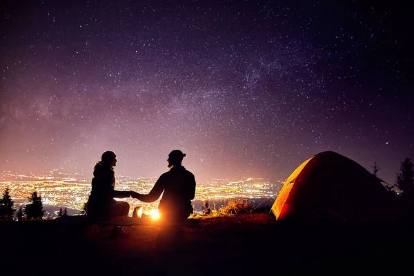 Romantic couple near campfire at starry sky