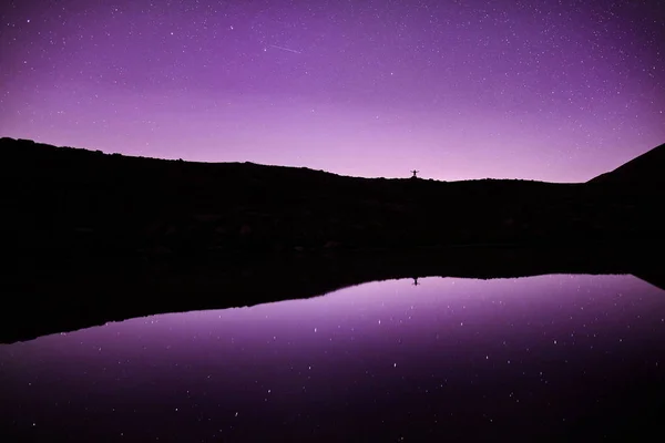 Hombre en las montañas en el cielo estrellado de la noche — Foto de Stock