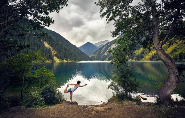 Mujer joven está practicando yoga al aire libre — Foto de Stock