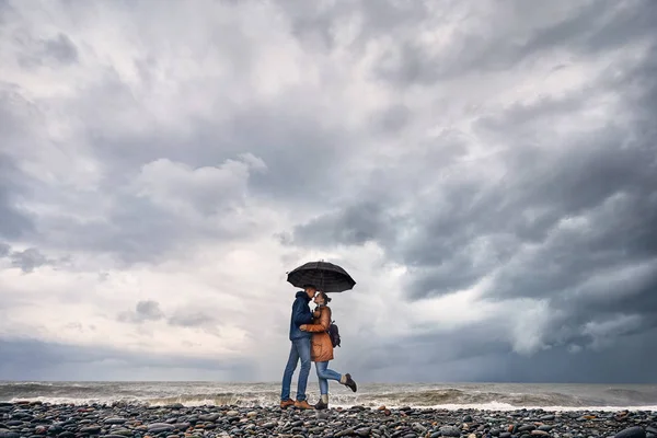Casal com guarda-chuva perto do mar tempestuoso — Fotografia de Stock