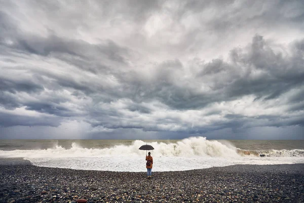 Vrouw met paraplu in de buurt van stormachtige zee — Stockfoto