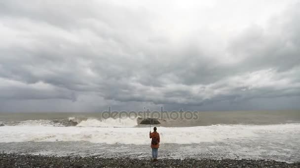 Frau mit Regenschirm nahe stürmischer See — Stockvideo