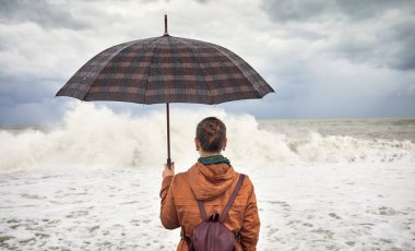Şemsiye fırtınalı deniz kenarında kadınla