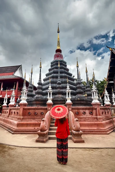 Frau mit rotem, traditionellem thailändischem Regenschirm blickt auf Black Temp — Stockfoto